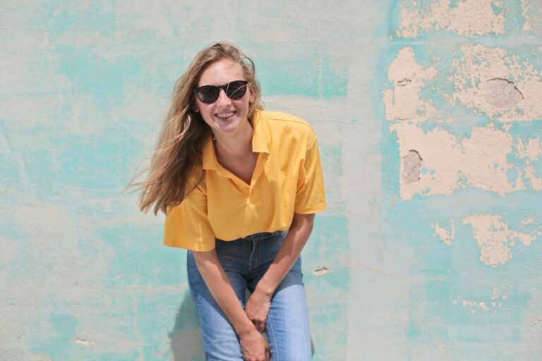 woman wearing yellow polo shirt standing in front of teal concrete wall